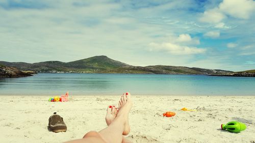 Low section of woman relaxing on sandy beach