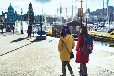 Rear view of people walking on road in city