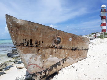 Graffiti on old boat at beach against sky