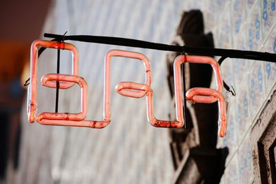 Low angle view of red lighting tube hanging outside shop