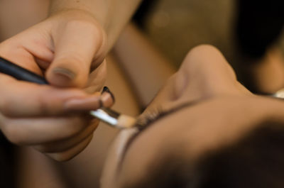 Cropped hand of beautician applying make-up to woman in spa