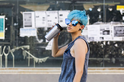 Portrait of young woman with dyed blue hair wearing mirrored sunglasses