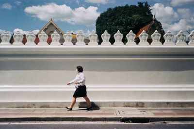 Full length of man walking against sky in city