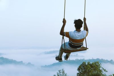 Rear view of man sitting on swing