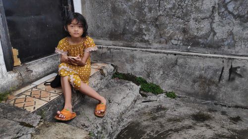 Cute little girl sitting in the back yard holding a cellphone