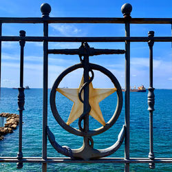 Close-up of metal railing against blue sea