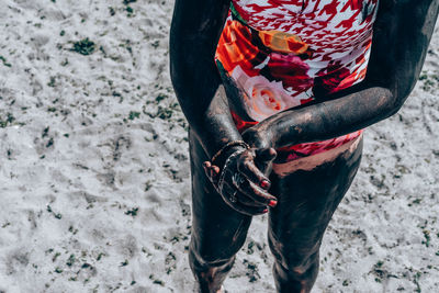 Midsection of woman with mud standing on sand at beach