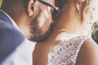 Bridegroom kissing neck of bride