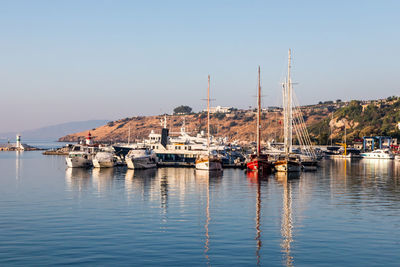 Sailboats moored in harbor against clear sky