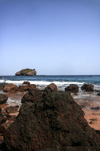 Rocks on beach against clear sky