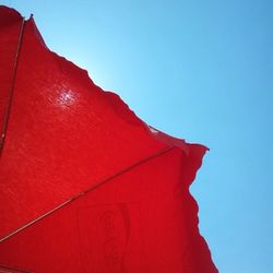 Low angle view of red wall against clear blue sky