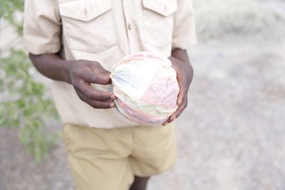 Mid section of a boy holding ball made of plastic packet