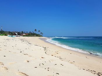 Scenic view of beach against clear blue sky