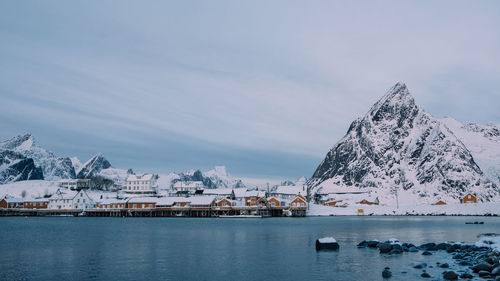 Scenic view of sea by snowcapped mountains against sky