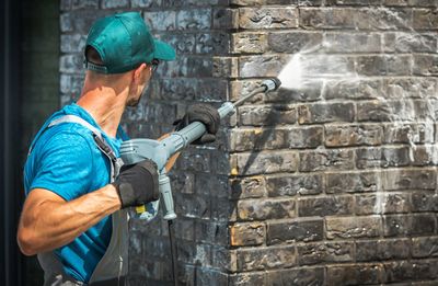 Side view of manual worker cleaning brick wall