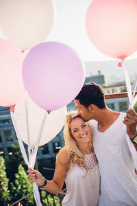 Portrait of smiling young couple holding balloons