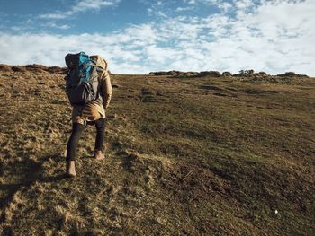 Rear view of woman walking on landscape against sky