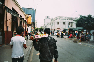 Rear view of people walking on street in city