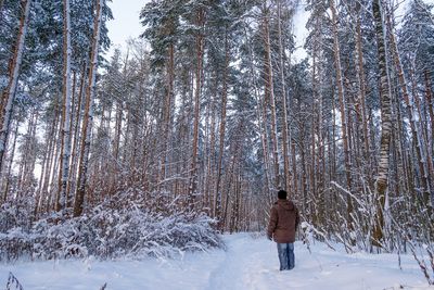 Rear view of woman walking on snow covered field