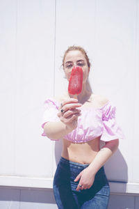 Portrait of woman holding flavoured ice against wall