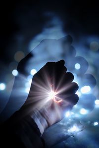 Close-up of hand against illuminated sun