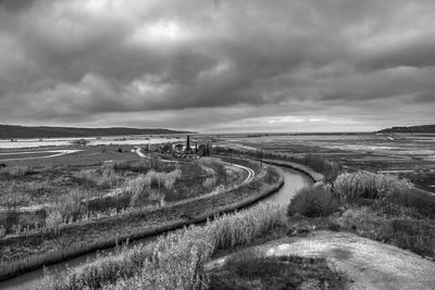 Panoramic view of road passing through landscape against cloudy sky