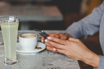 Midsection of businesswoman using smart phone in cafe