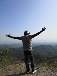 Rear view of man standing on mountain against sky