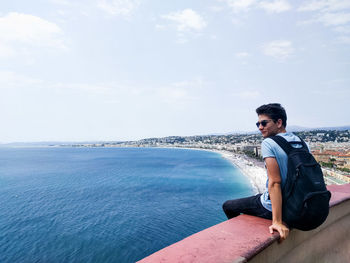 Side view of young man looking at sea against sky