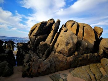 Rock formation on beach against sky