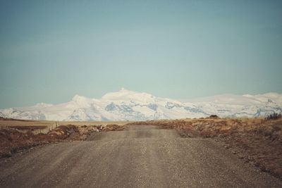 Road amidst snowcapped mountains against sky