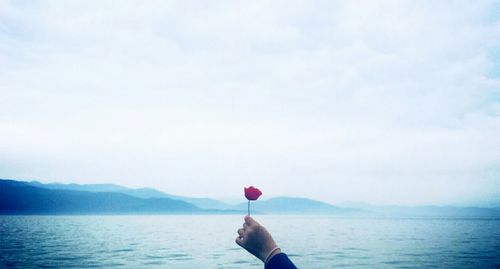 Rear view of woman holding water against sky