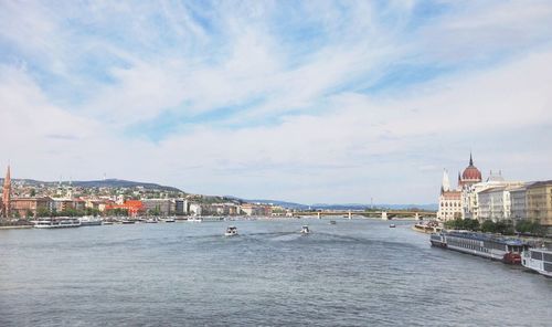 View of town by river against cloudy sky