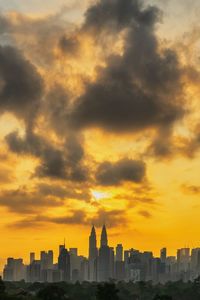 Buildings in city against cloudy sky at sunset