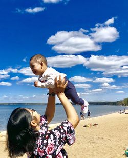 Father and son on beach against sky