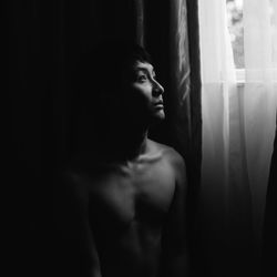 Young man looking through window