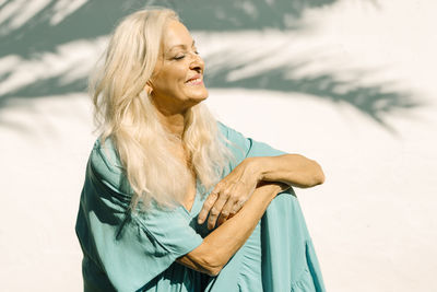 Smiling retired senior woman day dreaming at backyard on sunny day