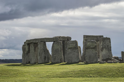 Stone structure on field against cloudy sky