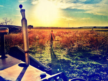 Man on field against sky during sunset