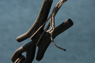 Close-up of rope tied to wooden post against sky