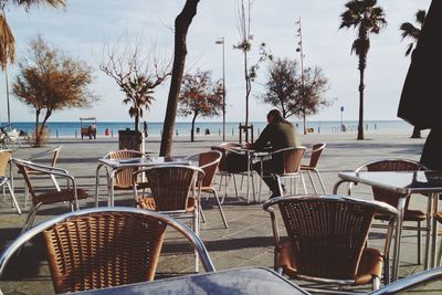 Rear view of man sitting at sidewalk cafe