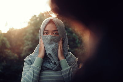 Portrait of young woman covering face with scarf