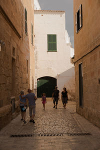 Rear view of people walking on street amidst buildings