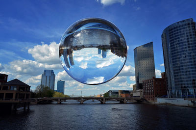 Low angle view of reflection on bubble over river against sky