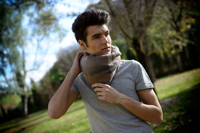 Young man wearing scarf while looking away at park