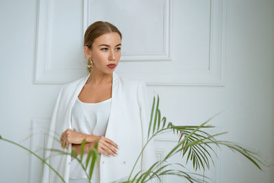 Young woman looking away standing against wall