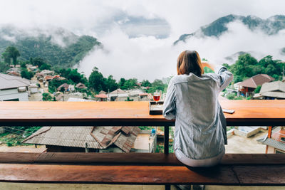 Rear view of woman standing on table against trees