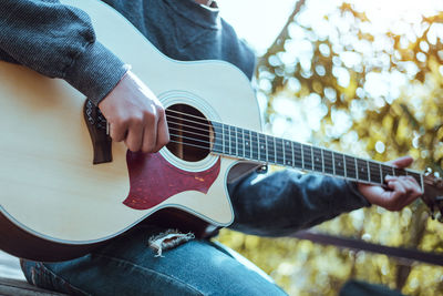 Midsection of man playing guitar