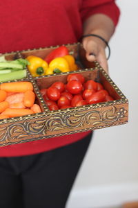 Midsection of woman holding container with various vegetables