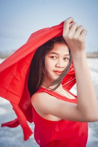 Portrait of beautiful young woman standing against red background